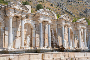Ancient fountain at Sagalassos city in Turkey features Corinthian columns and classical statues. Columns frame an ornate carved ceiling © Ensar