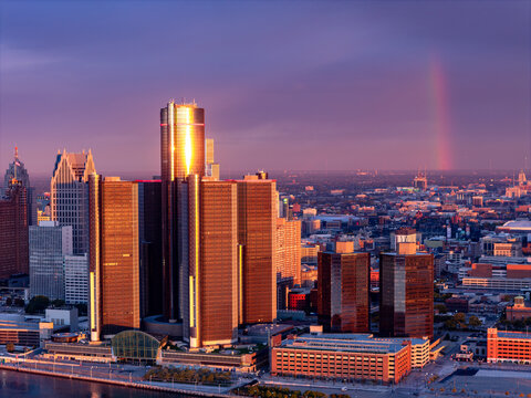 Aerial view of the Renaissance Center in Downtown Detroit illuminated by golden hour light with a faint rainbow over the city skyline in Detroit, Michigan, United States.