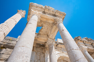 Corinthian columns frame an ornate carved ceiling at the Sagalassos ruins in Turkey. Ornate capitals crown towering columns beneath carved bands and a coffered ceiling © Ensar