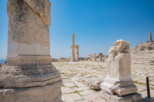Weathered columns border a broad paved ruin filled with carved stonework. Mountain slopes surround the ancient monuments of Sagalassos in southwestern Turkey