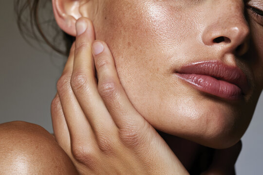 A close-up portrait showcasing a radiant face with natural glow, complemented by soft, sumptuous lips touching the cheek, exuding beauty and confidence.