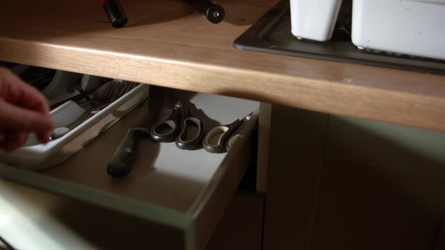 Hand opening green kitchen drawer and gets knife