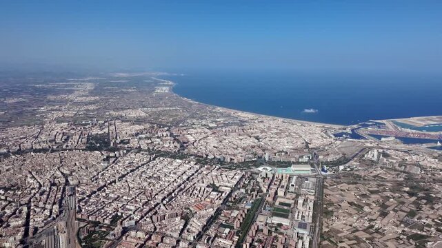 An aerial spinning view of Valencia city and outskirts, with a view of the harbor, Malvarrosa beach and north coast in a sunny summer day. 3000m high 4K shot.