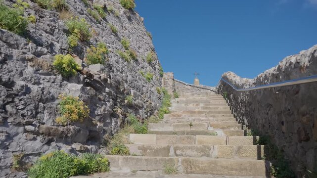 Stone steps ascending a historic path at San Juan de Gaztelugatxe, a coastal landmark in the Basque Country under clear blue sky