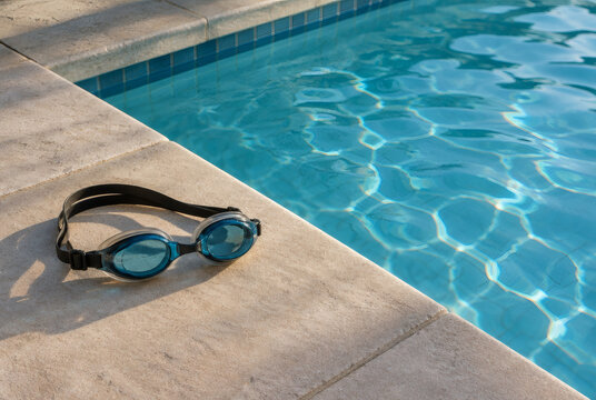 Swimming goggles beside a calm pool