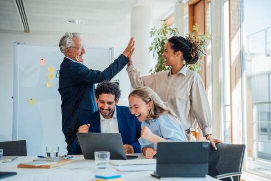 Business colleagues celebrate success with a laptop at the office