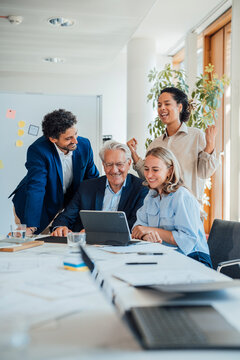 Business colleagues celebrate success while looking at a tablet