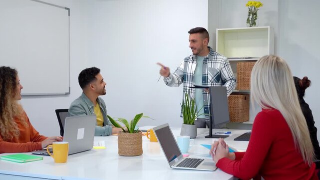 Young business manager giving a presentation to colleagues in a modern office. His team celebrates the success with applause and high fives