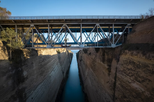 Aerial view of the Corinth Canal bridge spanning the deep, narrow limestone gorge with blue water below in Corinth, Greece.