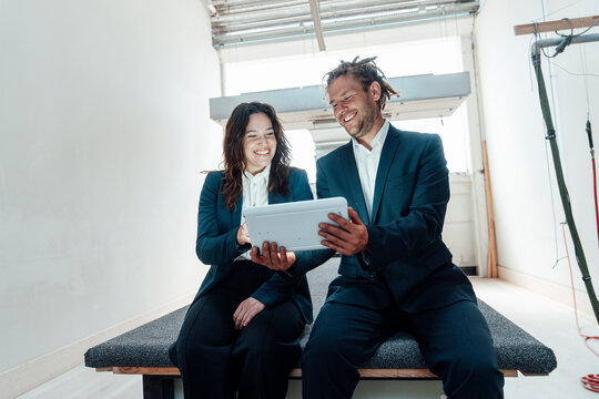 Man and woman in suits using tablet in a carpentry workshop