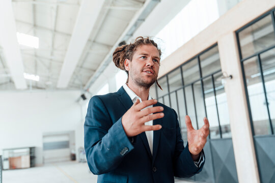 Unconventional businessman with dreadlocks gesturing in a workshop