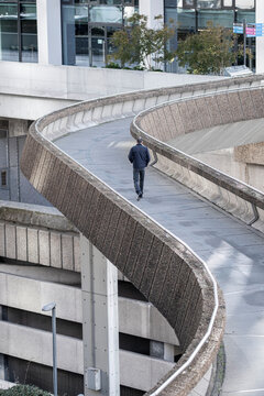 Curving pedestrian ramp in Paris France with a solitary person walking through a modern office district and contemporary urban architecture