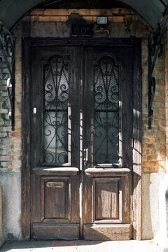 Weathered dark wooden entrance door with ornate wrought iron details and brickwork.