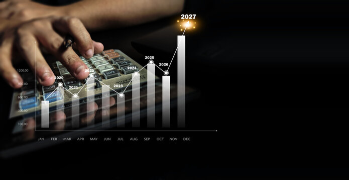 Person using a calculator to analyze business growth projection graph on a dark background with person uses calculator while digital bar chart displays annual financial growth projections 2020 2027