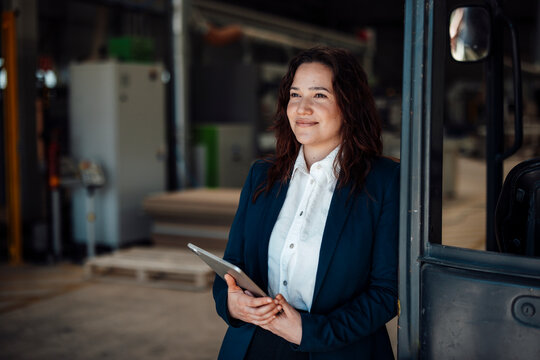 Smiling businesswoman holding a tablet in a carpentry factory