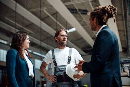 Woman and men discuss production in a carpentry workshop