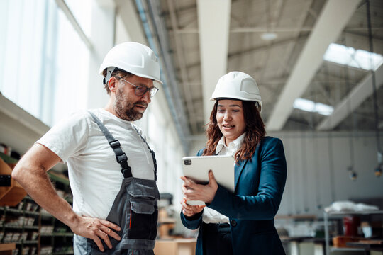 Engineer and carpenter discuss production plans on a tablet indoors