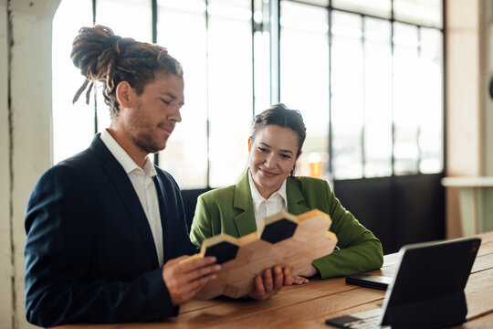 Man and woman discuss sustainable wood design sample in the office