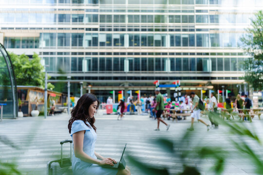 Professional woman works on laptop outdoors in modern city