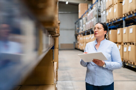 A female manager checks inventory on a tablet in a warehouse