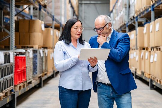 A businesswoman and a businessman check inventory in a warehouse