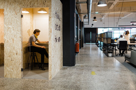 Young man works inside modern office pod