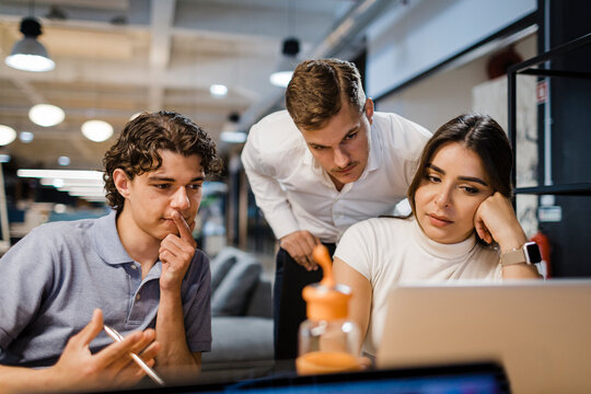 Colleagues collaborate on a laptop in a modern office