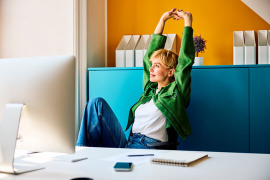 A businesswoman stretches at her desk in the office