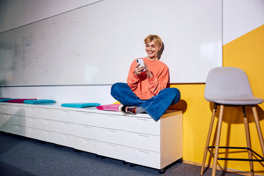 A cheerful businesswoman uses her smartphone in a modern office