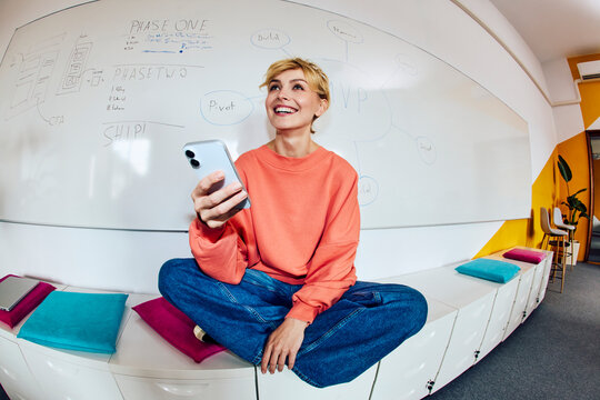 A cheerful businesswoman uses her smartphone in the office