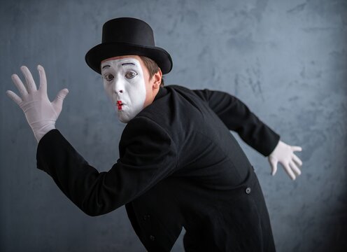 Funny mime actor in dynamic running pose with an astonished expression