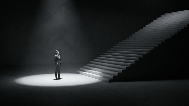 Man standing alone in a spotlight at the bottom of a dark staircase with spotlight staircase darkness silhouette conceptual contrast performance climbing aspiration standing solitude