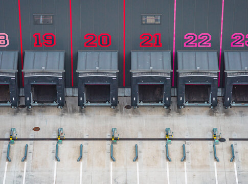 Aerial view of numbered loading docks and truck bays at a modern industrial warehouse and logistics distribution center with empty loading area in France.
