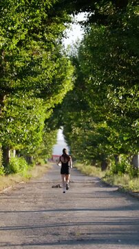 Beautiful Girl In A Black Sport Suit, Runs Along The Road In A Park