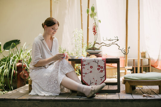 Beautiful young woman drinking jasmin tea sitting in a traditional chinese tea house.