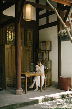 Beautiful young woman drinking jasmin tea sitting in a traditional chinese tea house.