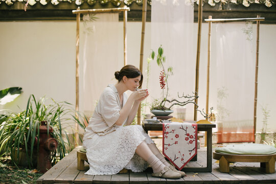 Beautiful young woman drinking jasmin tea sitting in a traditional chinese tea house.