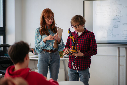 Teen boy explaining robotics project during science and technology class.