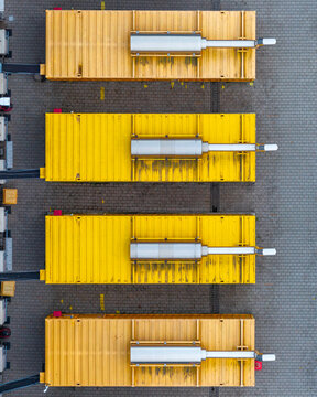 Aerial view of modular data center units with yellow containers and silver cooling systems arranged on a paved industrial site in Warszawa, Masovian Voivodeship, Poland.