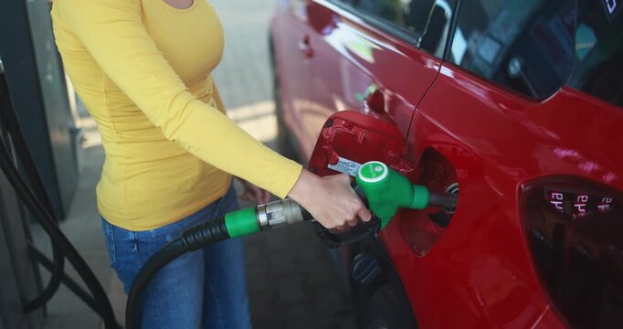Woman pumping gasoline fuel in car at gas station - Inflation, transport and rising fuel prices concept - Focus on hand - UGC content