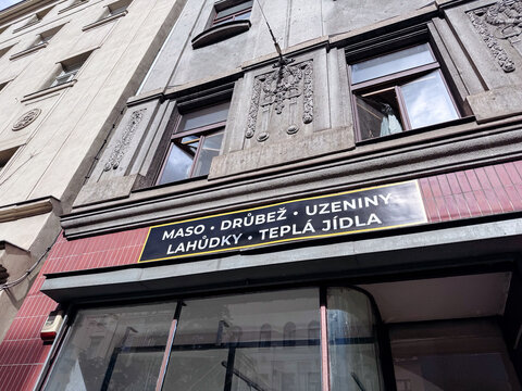 Prague, Czech Republic - September 21, 2026: Historic Art Deco facade with ornate stone panels above a Czech grocery sign reading maso, drubez, uzeniny, lahudky, tepla jidla