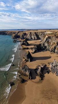 Aerial view of the dramatic rock stacks at Bedruthan Steps with sandy beach, rugged cliffs, and turquoise Atlantic ocean waves, Wadebridge, Cornwall, United Kingdom.