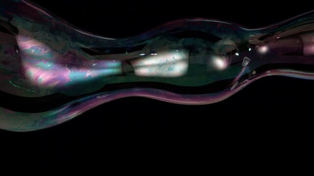 Highspeed Slowmotion shows an elongated iridescent soap bubble stretching and reshaping against a black background