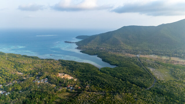 Aerial view of the lush mangrove forests and coastal hills of Karimunjawa, with turquoise waters and dense vegetation in Jepara Regency, Central Java, Indonesia.