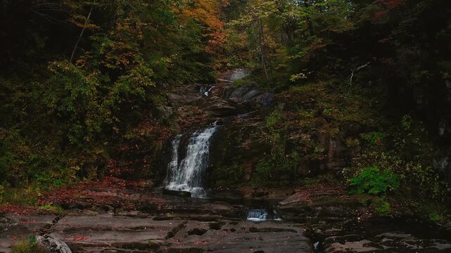 Drone pans backward over Enders Falls river revealing the lush forested landscape of Granby Connecticut
