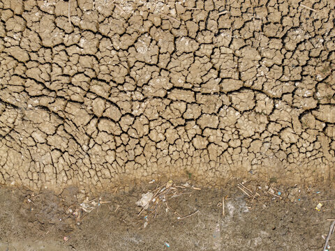 Aerial view of a dry, cracked riverbed with parched earth and scattered debris during the dry season in Kedung, Central Java, Indonesia.
