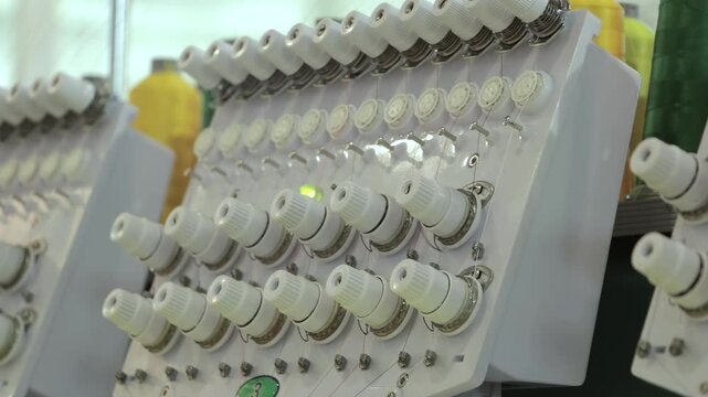 Close View of Thread Tension Controls on Embroidery Machinery. The footage documents textile equipment, material handling, stitching or machine controls in a workshop.