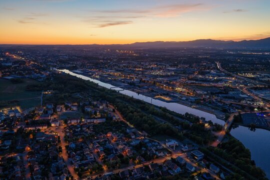 Aerial view of the illuminated canal and residential districts of Mulhouse at twilight, with road networks stretching towards the horizon in Mulhouse, Grand Est, France.
