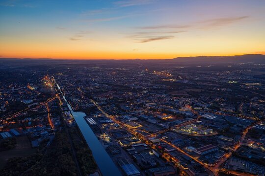 Aerial view of the illuminated cityscape and canal at twilight, Mulhouse, Grand Est, France.