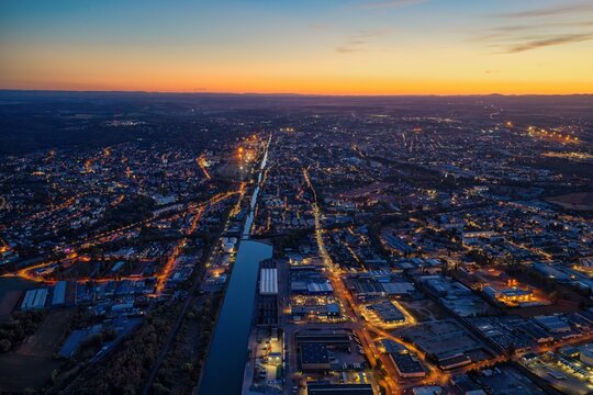 Aerial view of Mulhouse at twilight, featuring the canal cutting through the urban landscape with glowing street lights and buildings in Mulhouse, Grand Est, France.